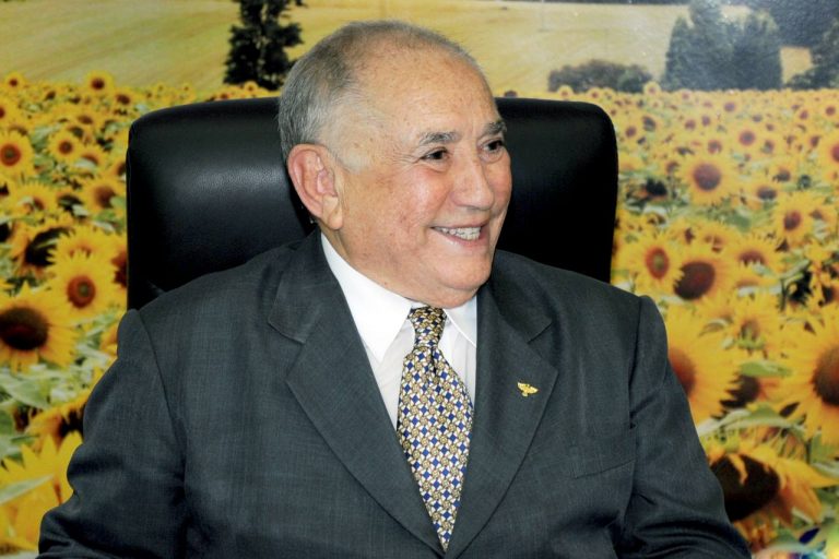 Um homem idoso sorri olhando para o lado